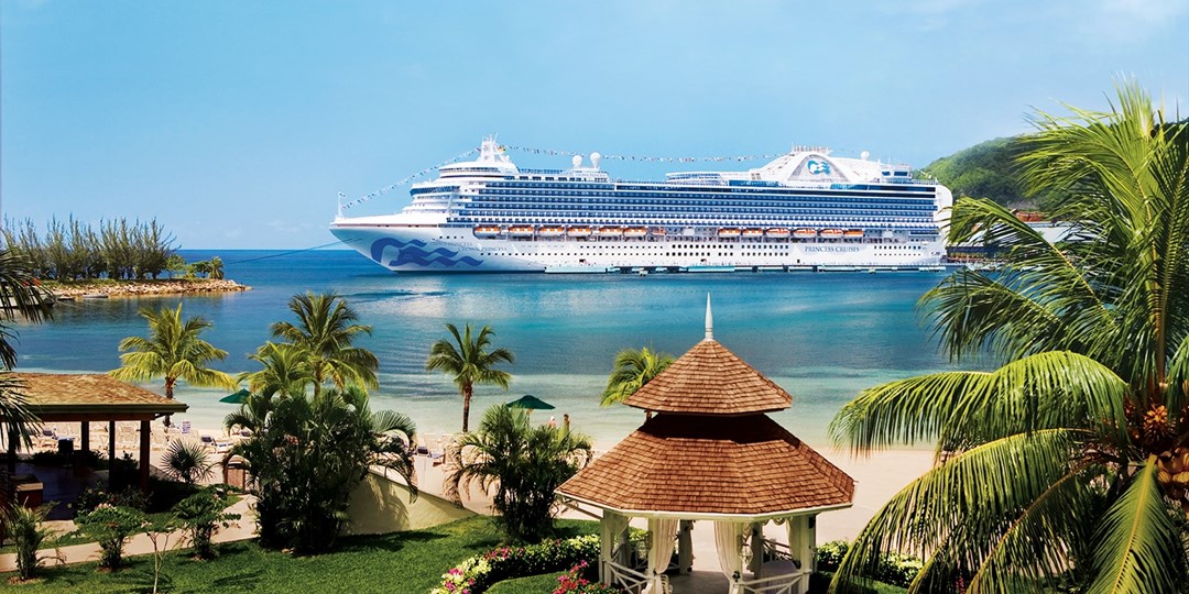 Kreuzfahrtschiff vor karibischer Insel mit türkisblauem Wasser